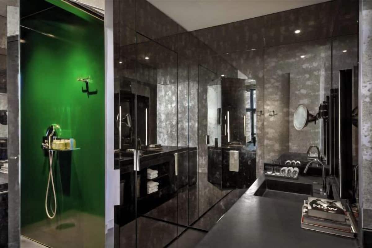 A modern bathroom with a glass shower enclosure, a large mirror, and a dark countertop.