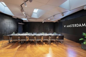 A conference room with a long table, chairs, and a black wall with 'W AMSTERDAM' text.