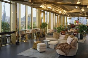 A spacious lounge area with a large sofa, chairs, and a bar area. - W Amsterdam (Amsterdam)