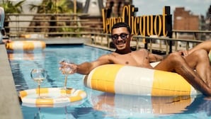 A pool area with a yellow and white inflatable float, a glass of wine, and a sign that reads "Venus Clicquot". - W Amsterdam (Amsterdam)