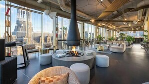 A modern lounge area with a central fire feature, comfortable seating, and large windows offering city views. - W Amsterdam (Amsterdam)