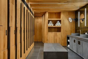 A modern bathroom with wooden cabinetry, a bench, and a vanity with a mirror. - W Amsterdam (Amsterdam)