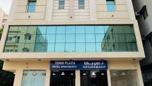 Un hotel de varios pisos con un letrero que indica "TOWN PLAZA HOTEL APARTMENTS".