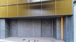 Une entrée moderne avec une rampe en métal, une porte ornée d’un logo et un sol à motifs.