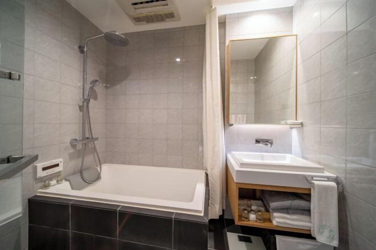 Ein modernes Badezimmer mit Badewanne, Dusche und Waschtisch mit Spiegel.