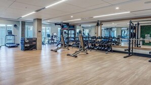 Ein geräumiger Fitnessraum mit Cardiogeräten, Gewichtstrainern und Spiegeln an den Wänden.