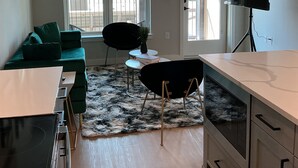 Eine moderne Küche mit Essbereich, einem grünen Sofa, einem schwarzen Stuhl und einem Fernseher.