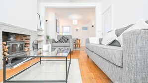 A modern living room with a glass coffee table, grey sofa, and a fireplace. - The Grove by Tŷ SA (Cardiff)