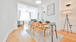 A modern dining area with a wooden table set for four, surrounded by chairs. - The Grove by Tŷ SA (Cardiff)