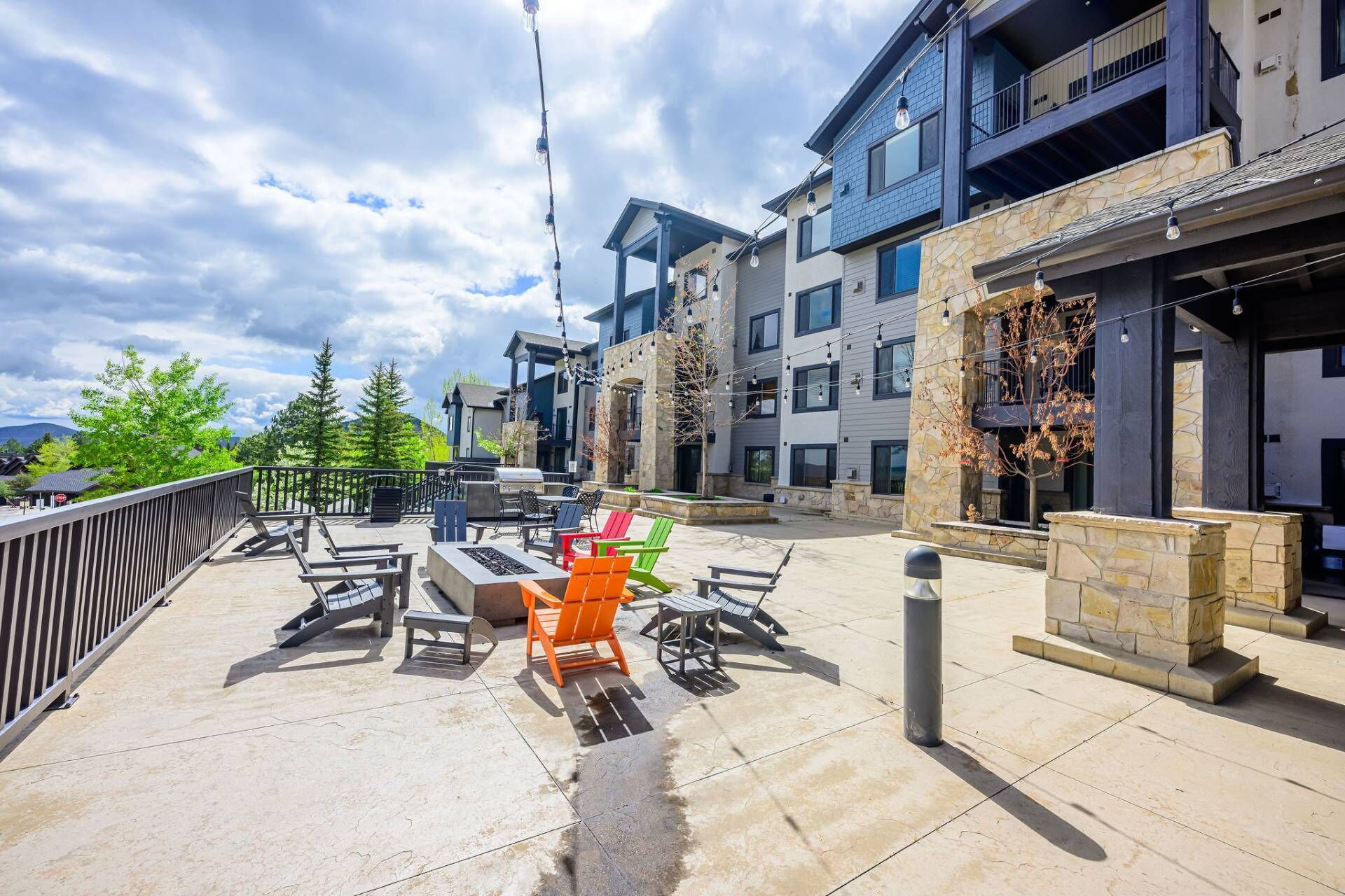Un patio al aire libre con mobiliario y una parrilla, rodeado de edificios de varios pisos con detalles de piedra y madera.