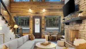 A modern living room with a large sectional sofa, a fireplace, and a stone wall.