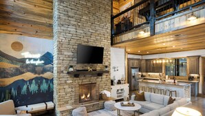 A spacious living area with a stone fireplace, a flat-screen TV, and a cozy seating arrangement.