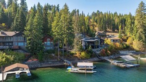 A lakeside property with multiple houses, docked boats, and a dock with a covered area. - Lakefront Hayden Lake Home with Private Dock for Family Getaways (Hayden)