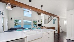 A spacious kitchen with a large island, wooden beams, and a view of the outdoors. - Lakefront Hayden Lake Home with Private Dock for Family Getaways (Hayden)