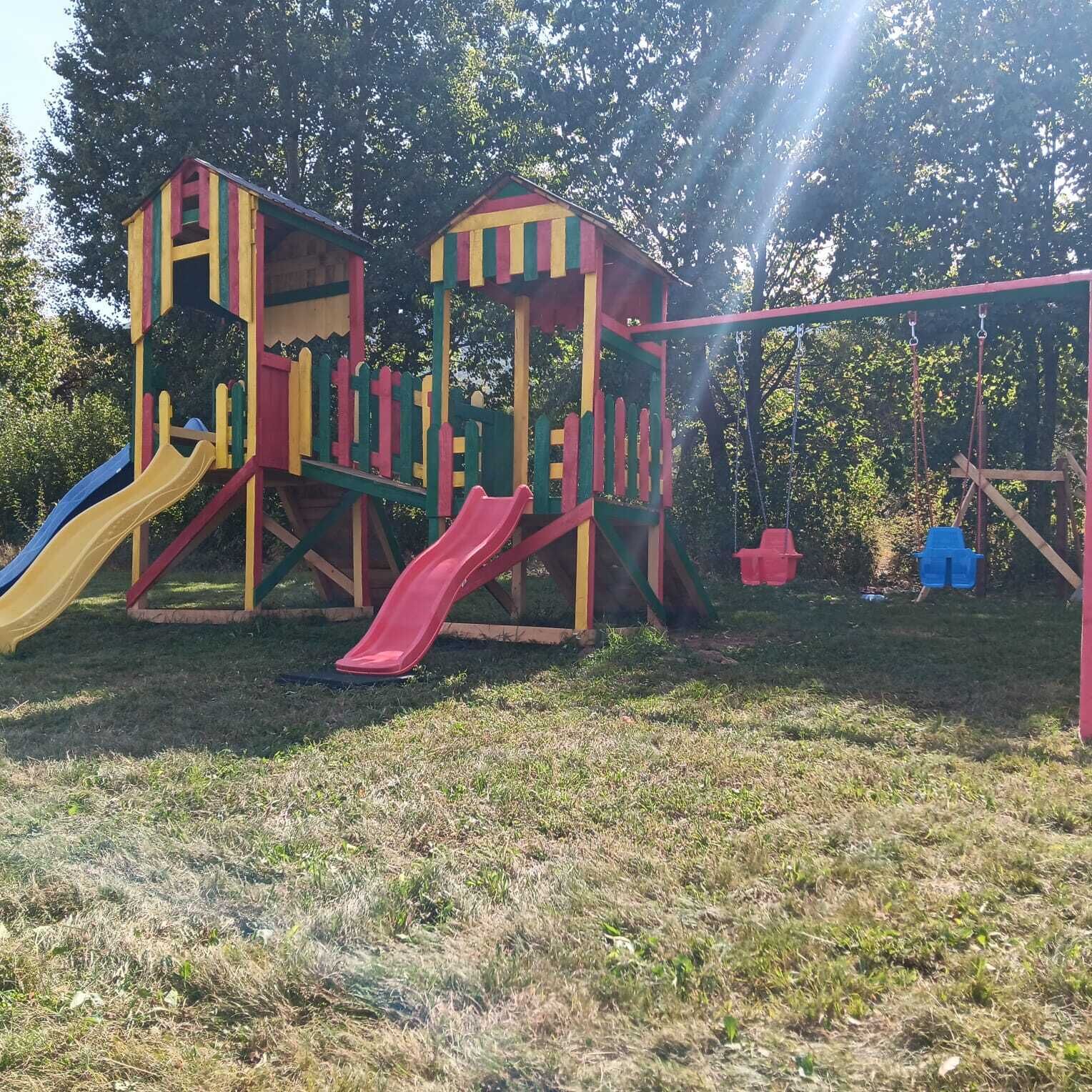 A playground with two slides and a swing set.