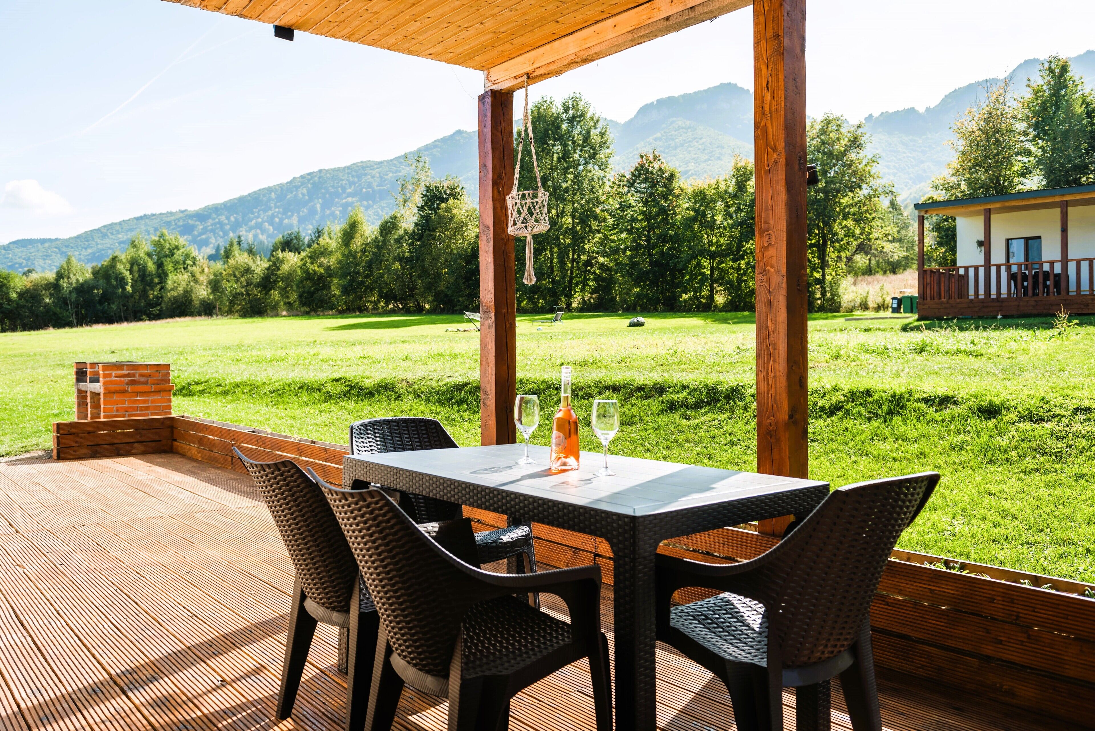 Un espacio de comedor al aire libre con mesa y sillas, con vistas a un campo cubierto de césped y montañas.