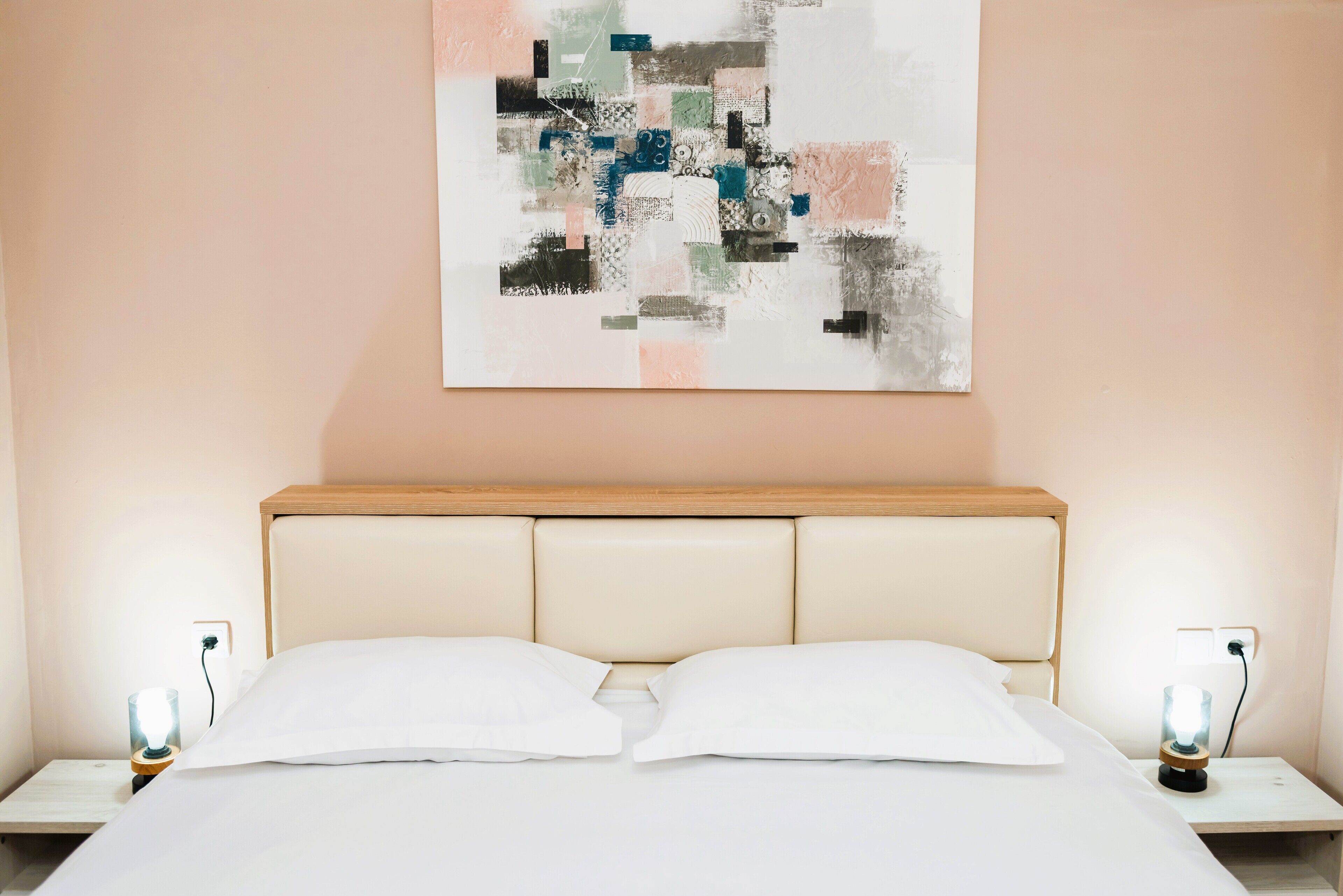 A neatly made bed with white linens and two bedside lamps on wooden nightstands.