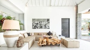 A modern living room with a sectional sofa, a unique wooden coffee table, and a large abstract painting on the wall. - Canggu PETER 2 (Bali)