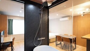A modern hotel room with a shower, a bathtub, a dining area, and a bed. - D-WASEDA (Tokyo)