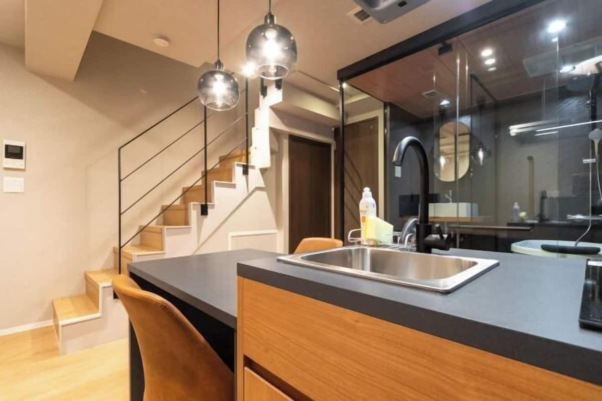 A modern kitchen with a built-in sink, wooden cabinets, and a staircase.