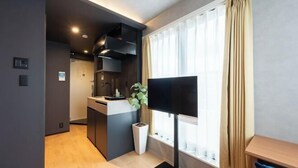 A modern hotel room with a kitchenette, a flat-screen TV, and a large window with curtains. - D-WASEDA (Tokyo)