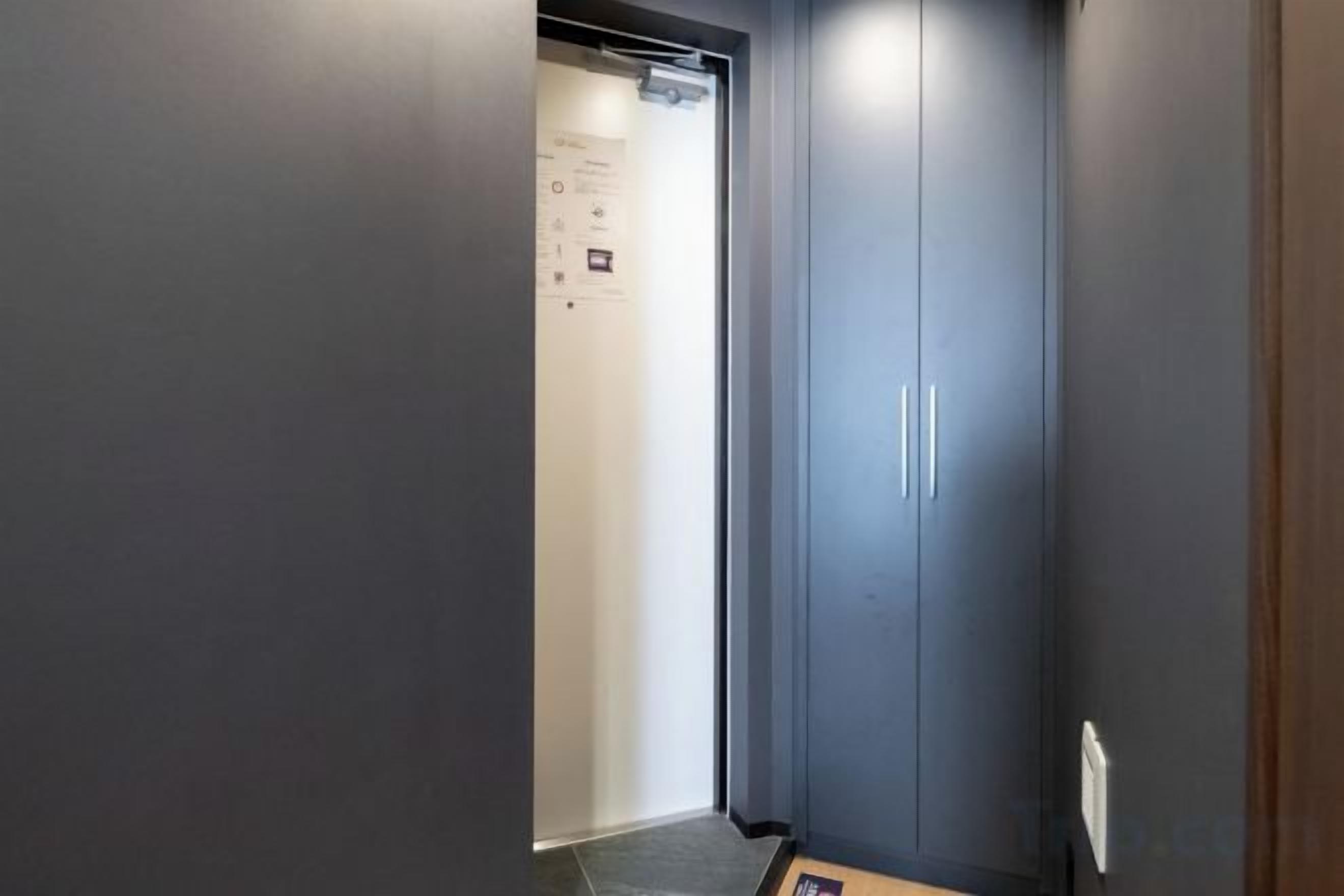 A narrow hallway with a door leading to a room.