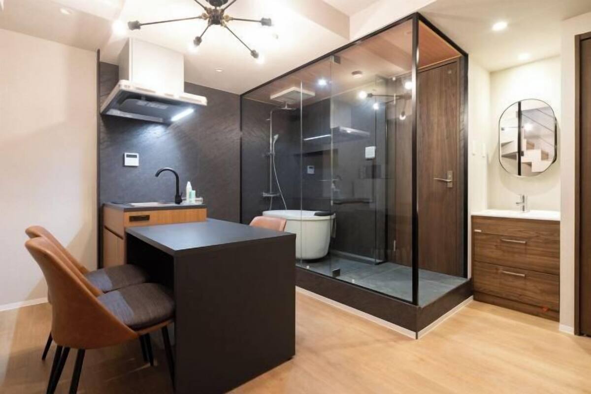 A modern kitchen with a central island, a glass-enclosed shower, and a wooden cabinet.