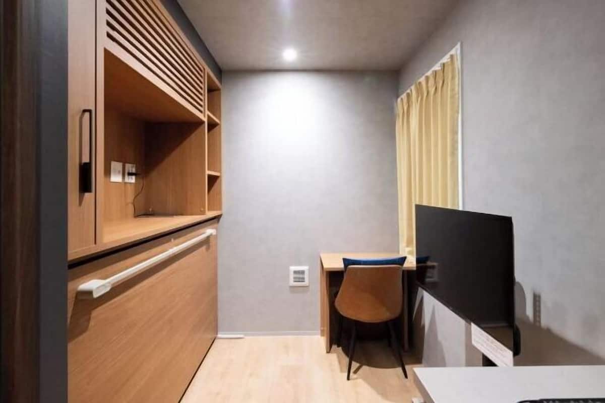 A compact room with a desk, chair, and a television.
