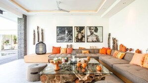 A modern living room with a glass coffee table, a grey sofa, and artwork on the wall.
