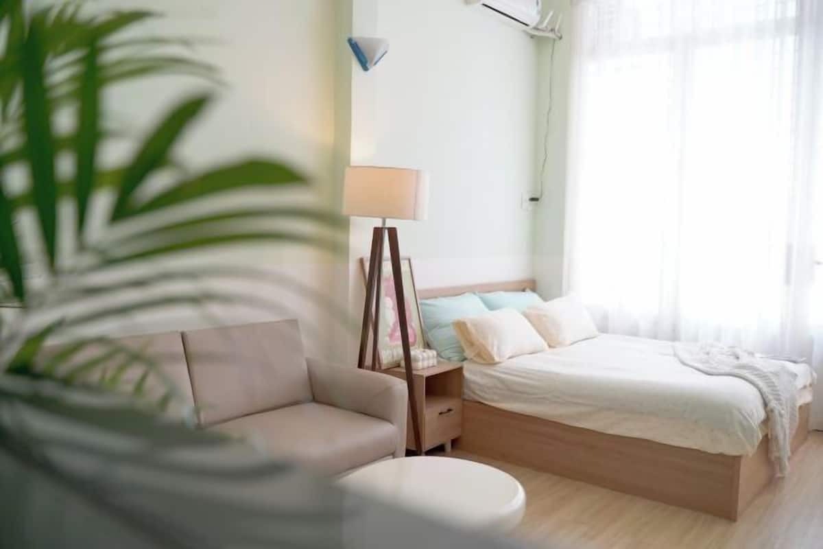 Une chambre à coucher avec un lit, une table de chevet, une lampe et une plante en pot.