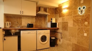 A compact kitchen with a washing machine, a microwave, and a coffee maker.