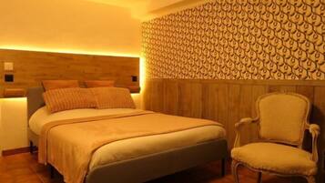 Una camera da letto con testiera in legno, un letto con copriletto color beige e una sedia coordinata.