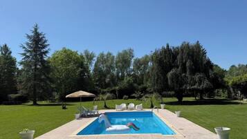 A rectangular swimming pool with a lounge chair and a small inflatable float.