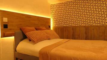 Una camera da letto con una testiera in legno, un letto con coperta beige e una parete decorata.