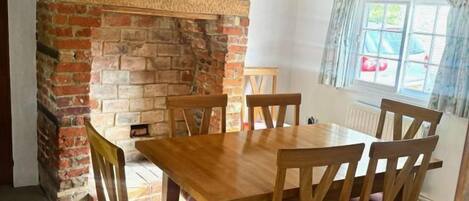 Un comedor con chimenea de ladrillo, mesa de madera y sillas.