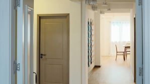A hallway with a door, a dining area with a table and chairs, and wall-mounted artwork. - Private Full-Floor Spacious 5 Bedrooms in China Town (Bangkok)