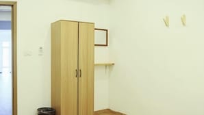 A room with a wooden wardrobe, a small trash bin, and a wall-mounted shelf. - Private Full-Floor Spacious 5 Bedrooms in China Town (Bangkok)