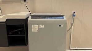Lavadora compacta y moderna con panel de control, cable de alimentación y manguera de agua.