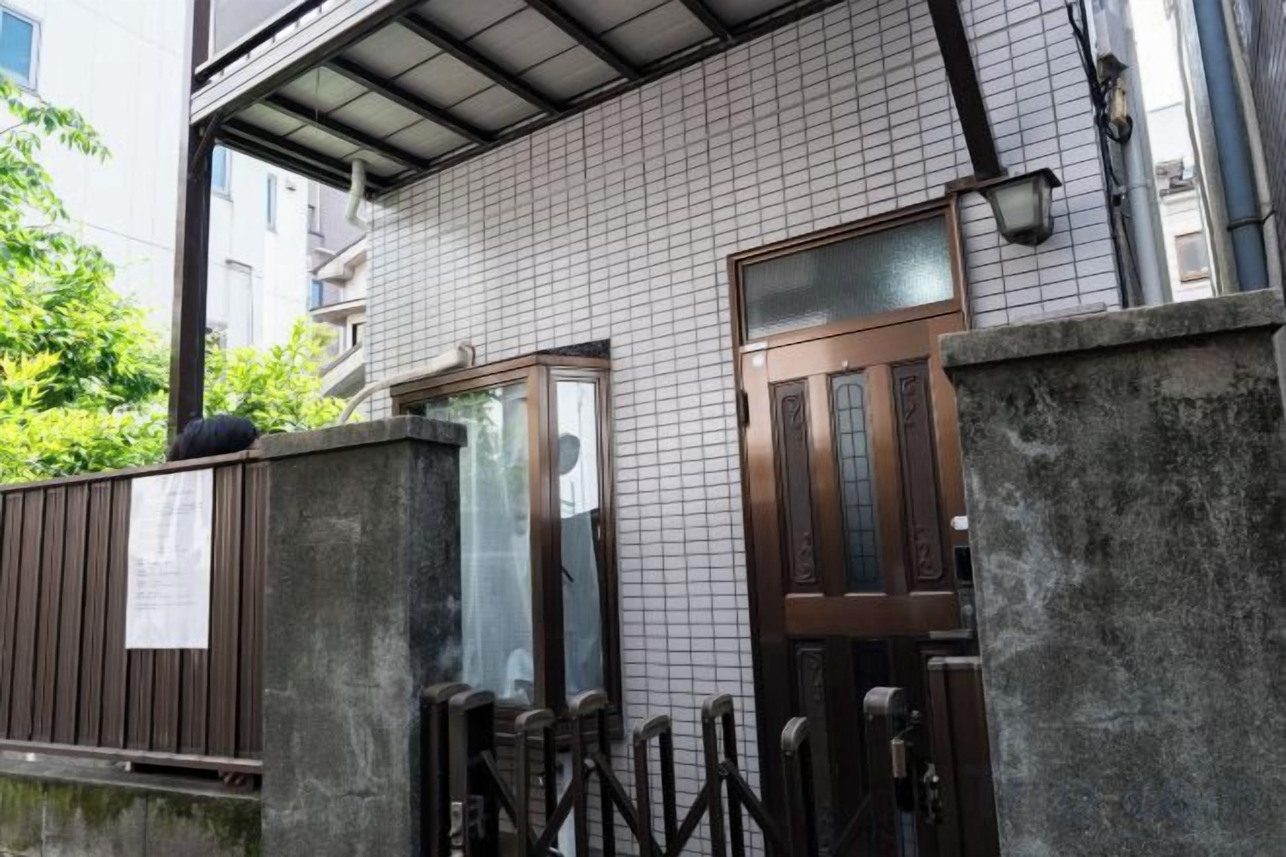 A building with a tiled exterior, a wooden door, and a metal gate.