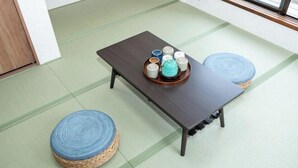 A tatami mat room with a low table, a tray with cups, and two woven stools. - Kaike・Honcho detached house (Tokyo)