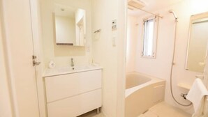 A bathroom with a sink, mirror, and bathtub. - BASE36 (Tokyo)
