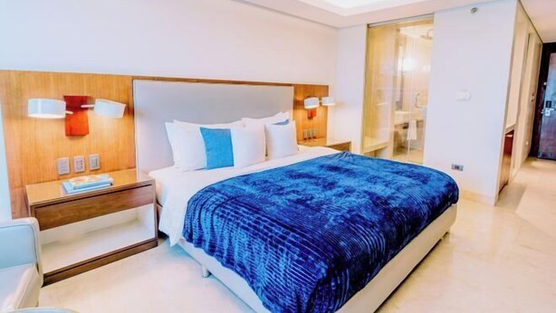 Een moderne hotelkamer met een groot bed, nachtkastjes en een zichtbare badkamer door een geopende deur.