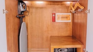 A wooden cabinet with a microwave, a red container, and wooden hangers. - MCollection - Convenient City Stay in Iloilo Business Park (Iloilo City)