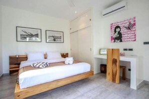 Une chambre à coucher moderne avec un lit en bois, du linge de lit blanc, un bureau et deux tableaux encadrés au mur.
