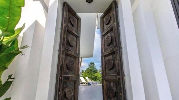 A corridor with open wooden doors leading to a balcony with a view of trees and a clear sky. - Villa Lotus, 3 Bedrooms (Koh Samui)