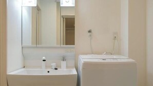 Een badkamer met een wastafel, spiegel en een witte wasmachine.