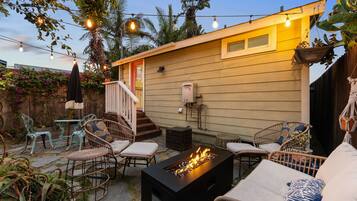 A backyard with a fire pit, outdoor furniture, and string lights.