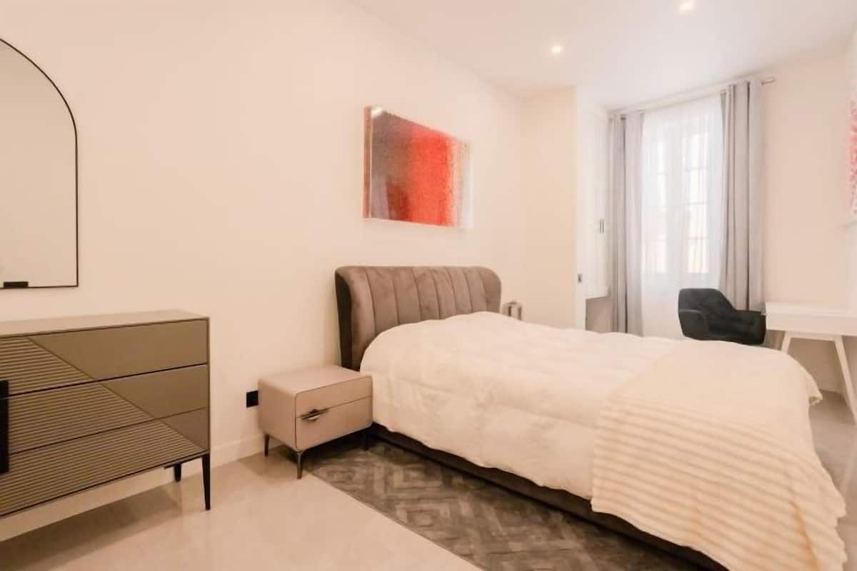 A modern bedroom with a bed, bedside table, and a desk.