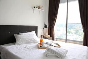 Habitación de hotel con cama, bandeja de desayuno, ventana con cortinas y vista a la ciudad.
