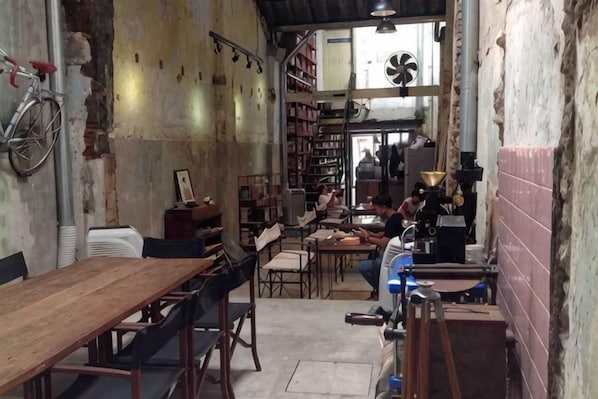 A rustic interior with wooden tables and chairs, a bicycle, and a fan. - Phuket Town Budget House - Aircon Room #1 (Phuket)